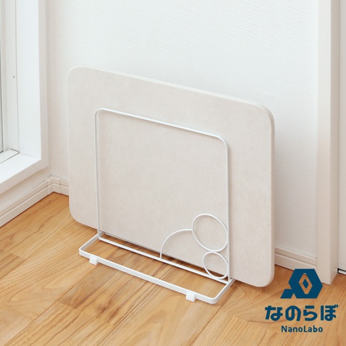 雙面珪藻土瞬間吸水地墊，米白色，厚實，圓角設計，立於白色金屬支架上，置於木質地板與白色牆壁的角落。