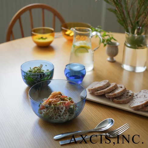 LAGOM 清透復古圓潤點心碗，藍色玻璃碗盛裝著義大利麵，另有綠色沙拉碗、藍色小杯、玻璃水壺及切片麵包，擺設於木質桌面。