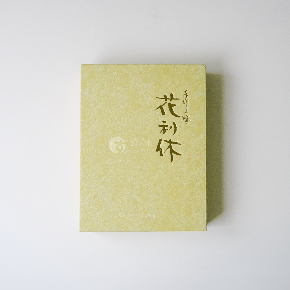 淡黃色的矩形禮盒，包裝表面帶有細緻的漩渦紋理，中央右側以黑色書法字寫著花利休，左下角則有河內駿河屋的品牌圓形標誌，整體呈現典雅精緻的日式風格。