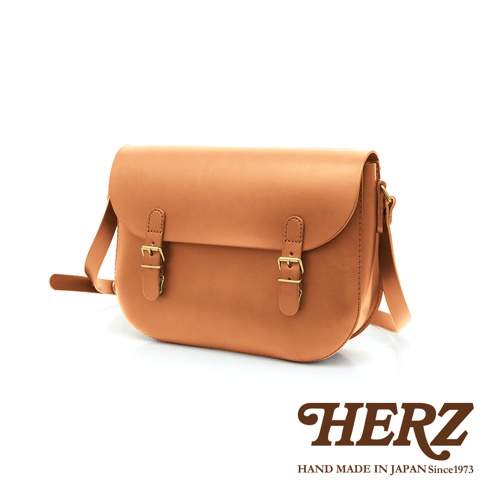 職人手作皮革經典馬鞍包，採用天然棕褐色皮革，配有兩個金色搭扣和可調節皮帶。包身線條流暢，風格簡約復古。