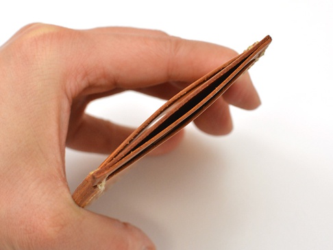 職人手作皮革直式票券收納夾，棕色皮革，夾層可見，由手指握持。