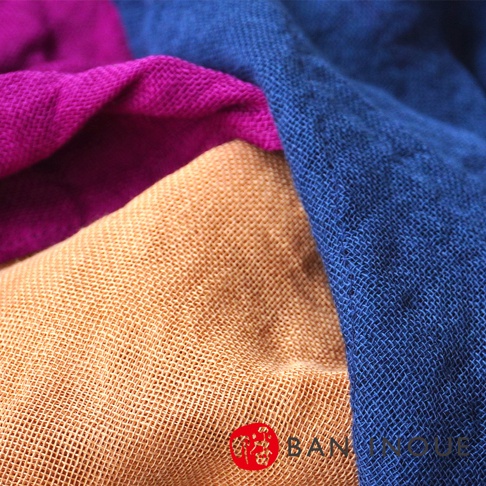 三種顏色織物特寫：寶藍色、桃紅色和淺棕色。織物材質呈現細緻的網格狀紋理，堆疊在一起，營造出柔軟且有質感的視覺效果。