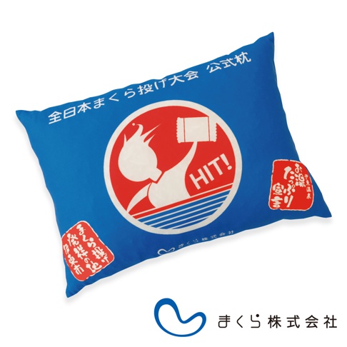 藍色小抱枕，表面印有白色與紅色圖案，中央是圓形標誌，包含一個白色人物持票券、標示「HIT!」，下方有藍色線條。抱枕兩側有紅色方形標籤，印有白色日文。