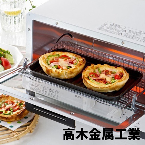 日本製烤箱用黑色波浪長形烤盤，內有兩個烤好的圓形派，派皮金黃酥脆，餡料包含番茄、青椒、火腿和融化的起司。