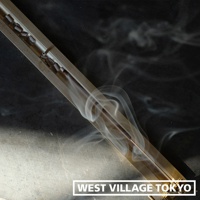 黃銅夾式水平線香架，線香燃燒中，散發白色煙霧，整體呈金屬光澤，置於深色背景上。