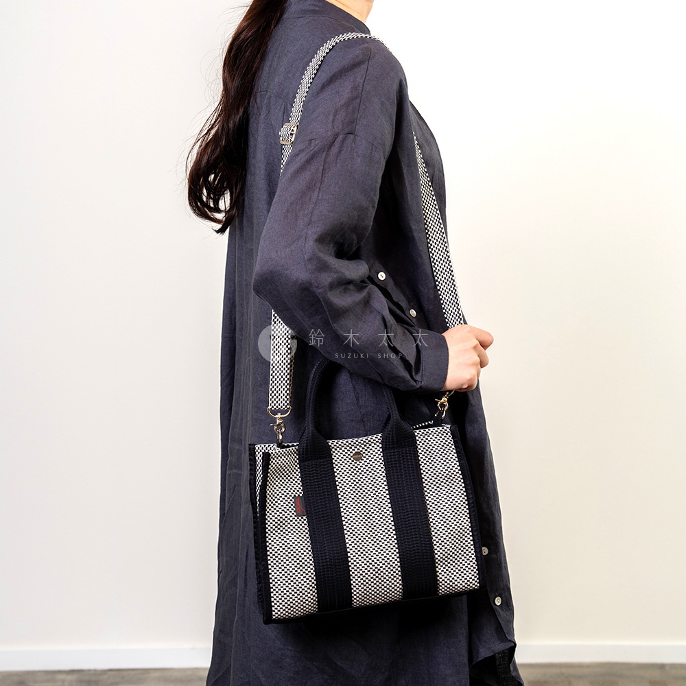 三河木綿刺子織兩用方形托特包，採用黑白直條紋設計，搭配格紋肩帶，展現簡約風格。