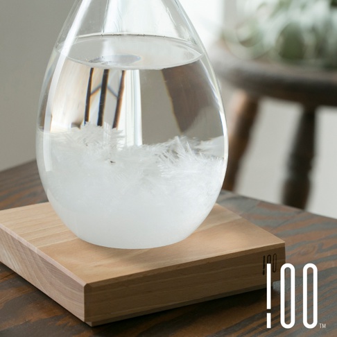 一個裝有清澈液體和白色結晶的梨形玻璃瓶，放置在一個淺色木製方形底座上。