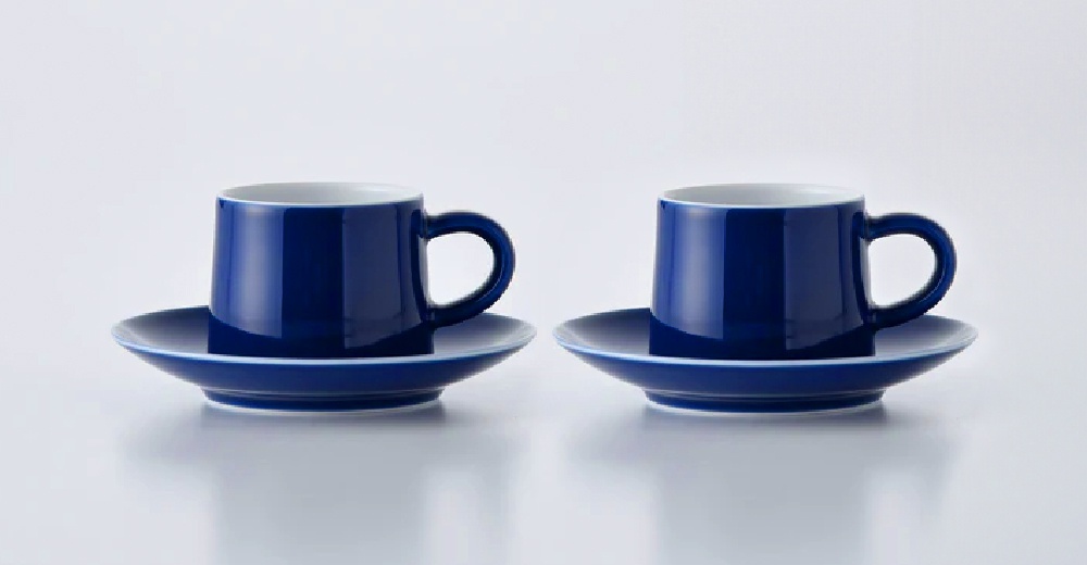 兩組藍色陶瓷咖啡杯與杯盤，杯身呈圓柱形，帶有圓形把手，杯內為白色。