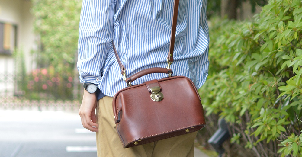 職人手作皮革方型迷你醫生包，採用棕色光滑皮革製成，配有金色金屬扣和提把，可肩背或斜背。