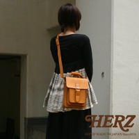 皮革單肩兩用小方包，淺棕色，附有手柄和可調節肩帶，包身有明顯的縫線和金屬釦環。