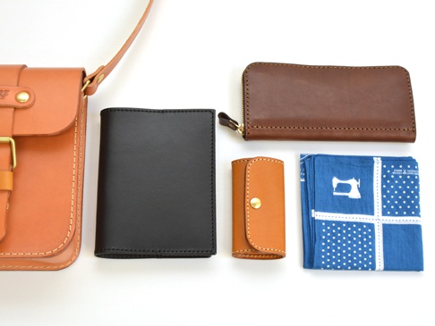 棕色皮革單肩包、黑色皮革皮夾、棕色皮革鑰匙包和藍色印花手帕。