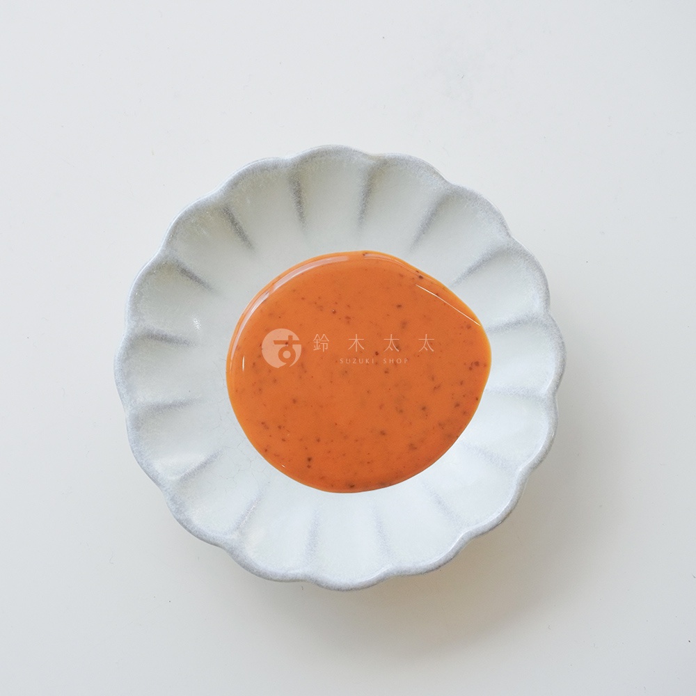 一碗盛有北海道芝麻擔擔風味沙拉醬的白色荷葉邊盤子，上面印有「鈴木商店 SUZUKI SHOP」的標誌。