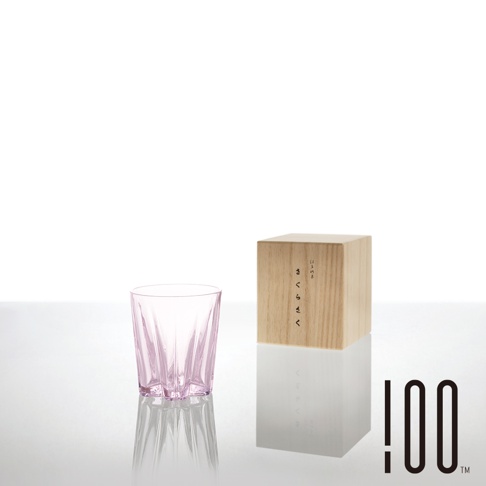 淺粉色玻璃製成的櫻花清酒杯，杯身帶有放射狀的紋路，置於白色背景上，旁邊有一個寫有日文「さくらさく」的木盒。