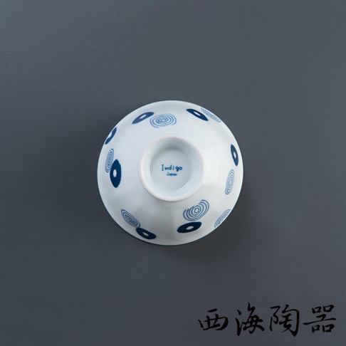 白色陶瓷飯碗，碗身飾有藍色圓形與漩渦紋飾，碗底印有「Indigo Japan」字樣。