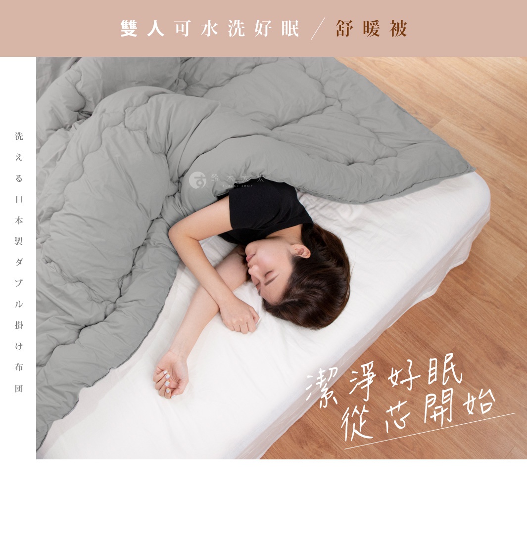 女性蓋著灰色雙人舒暖被，被子材質柔軟蓬鬆，呈現絎縫紋路，鋪蓋在白色床單上。