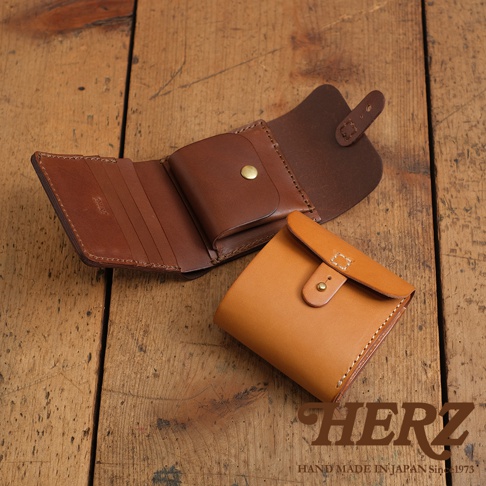 兩款職人手作皮革短夾，一款為棕色、展開狀態，展示多個卡槽及零錢袋；另一款為淺棕色、閉合狀態，使用原子釦固定，皮革紋理清晰，質感溫潤。