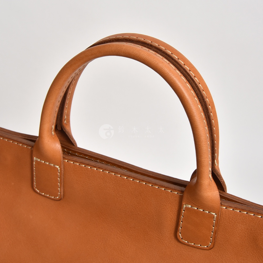 職人手作皮革大容量兩用托特包 T-8，採用自然棕色皮革，配以手工縫線，提把設計圓潤，展現細膩質感。