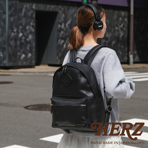 黑色皮革休閒風後背包，配有雙拉鍊主隔層、前方拉鍊口袋及側邊插袋。包款採用真皮材質，風格簡約。