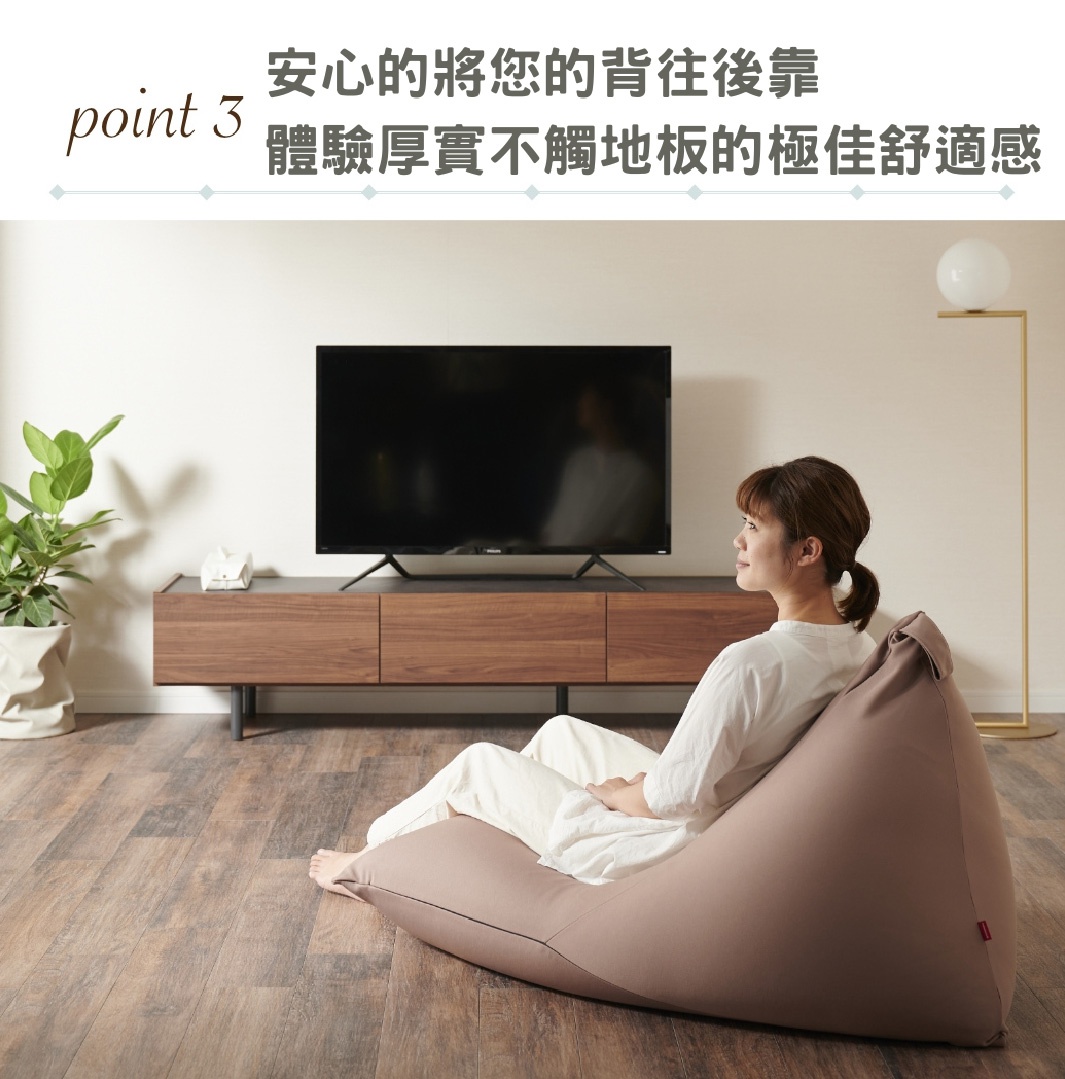 一位女子坐於駝色針織布款懶骨頭沙發上，沙發置於木地板上，後方為電視櫃與電視。