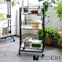 黑色金屬三層置物推車，搭配木質層板，其中一層擺放有植物、罐子和噴霧瓶，另一層有罐子，最底層有收納盒、綠色盒裝物及布料。推車底部有四個輪子。