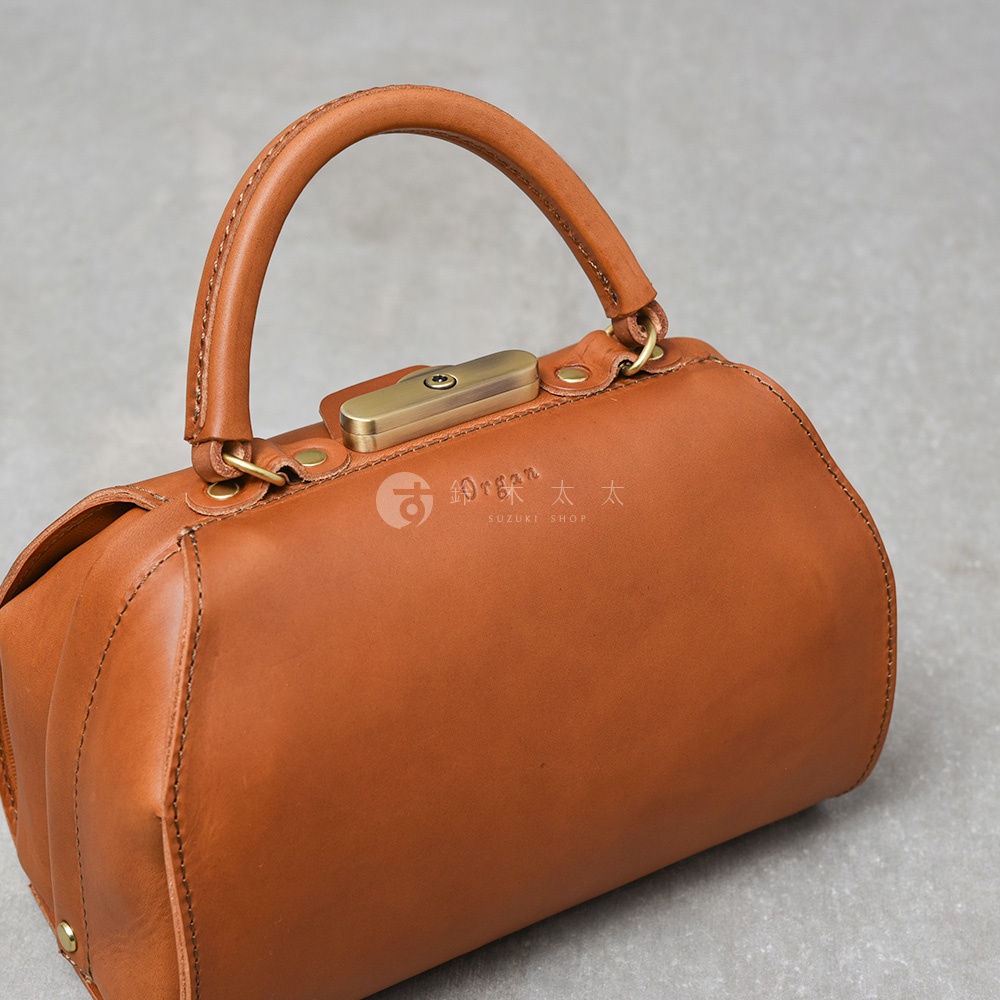 職人手作皮革Organ兩用口金手提包，呈現經典醫生包造型。包身為溫潤的棕褐色皮革，搭配復古金屬口金與提把，整體散發質感。