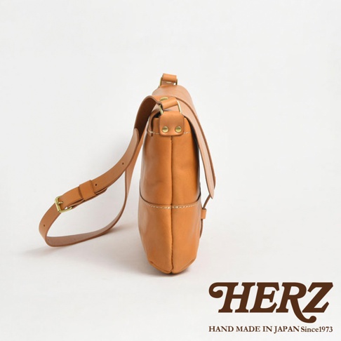 HERZ 職人手作皮革細扣帶馬鞍包，駝色皮革材質，側面視角，展現精緻工藝。