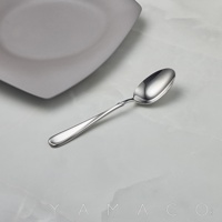 Flora系列不鏽鋼湯匙，銀色，湯匙造型優雅，上方擺放著灰色盤子，背景為白色大理石紋桌面