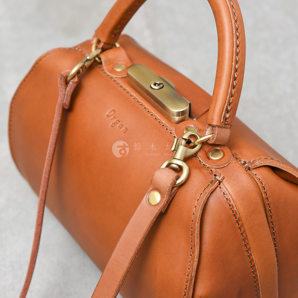 職人手作皮革Organ兩用口金手提包，深棕色皮革，圓筒形包身，配有黃銅色金屬鎖扣、提把及可拆卸肩帶。