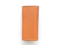 職人手作經典鑰匙包，採用淺棕色皮革製成，有四個鉤扣，以白色車縫線裝飾，外觀簡潔。