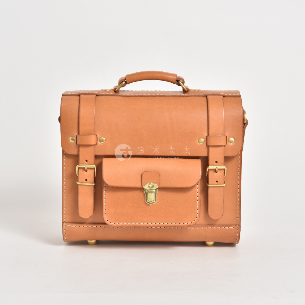 職人手作學院風三用迷你後背包，採用天然皮革材質，呈現溫潤的淺棕色。設計簡潔，帶有翻蓋前袋、金屬鎖扣、可調節式皮帶及搭扣，以及頂部提把。