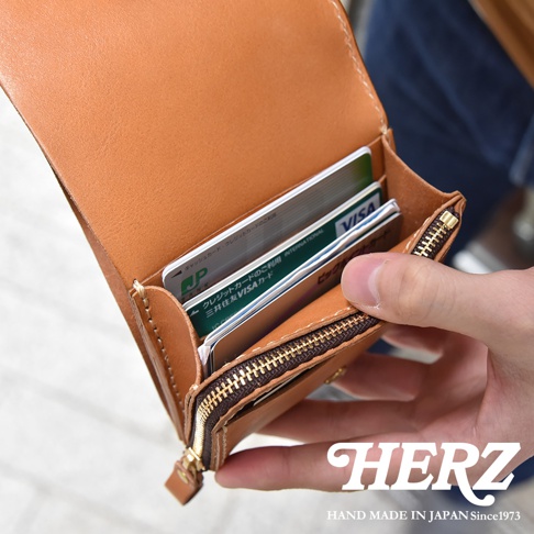 職人手作皮革小型雙折短夾，展示棕色皮革材質，內部有卡片插槽，裝有多張信用卡。