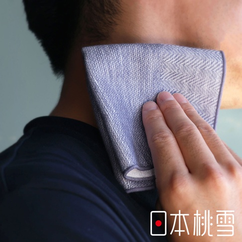 一隻手拿著一塊藍色人字紋的紗布方巾擦拭臉頰。