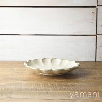 一個米白色、六瓣花型、邊緣略帶復古紋理的陶瓷主食盤，置於木製桌面。