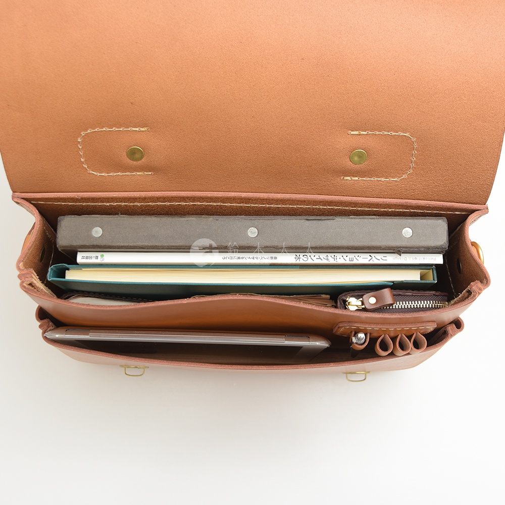 職人手作皮革極簡風三用商務公事包，棕色皮革，內部可見數本筆記本、平板電腦、一個小錢包，以及筆插。