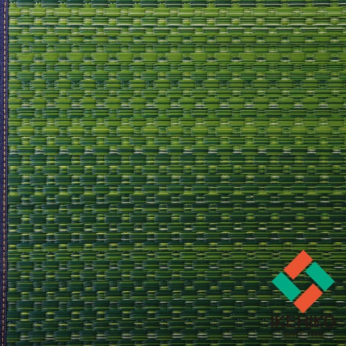 藺草編織的瑜珈墊，主體為深淺不一的綠色，呈現橫向的紋理，左側邊緣有深藍色滾邊。