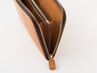 職人手作皮革長夾，淺棕色，採用拉鍊開合設計，露出內部隔層與細緻縫線，展現皮革質感。