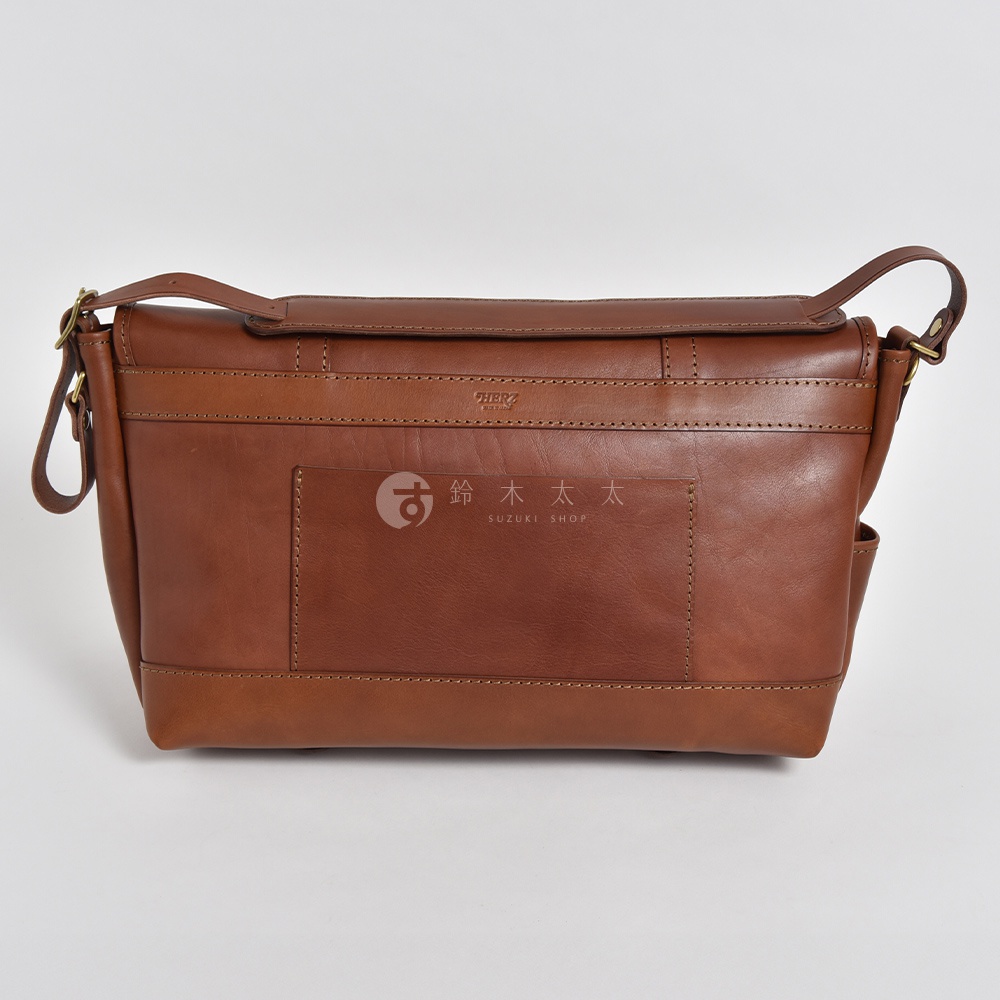 職人手作皮革復古郵差包 CM-100，採用棕色皮革製成，帶有精緻縫線和金屬扣環，設計簡約實用。