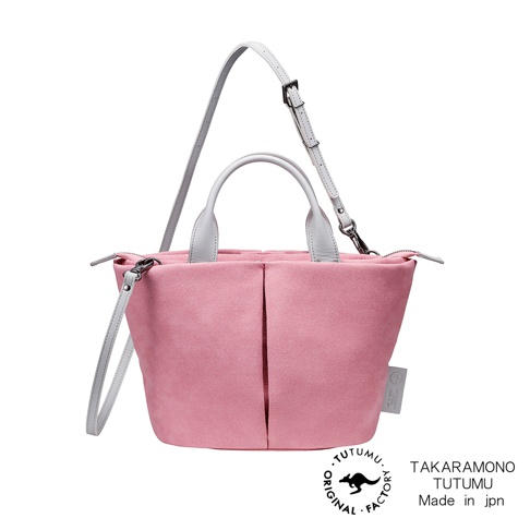 粉紅色麂皮材質的 TUTUMU Suede Marche petit 兩用單肩包，搭配淺灰色提把和揹帶，包身有雙褶設計，並附有品牌標籤和圓形標誌。