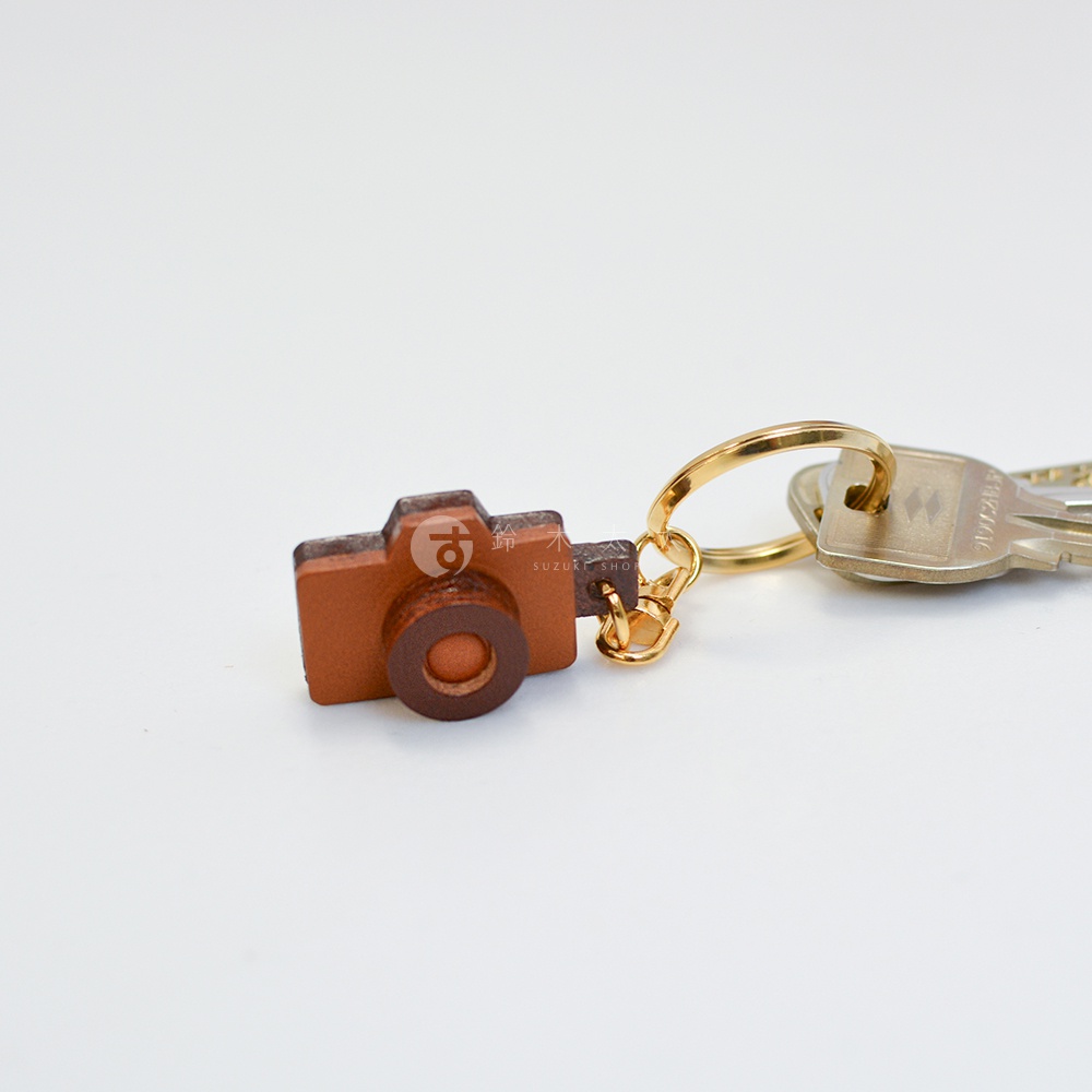 職人手作皮革相機造型鑰匙圈，以棕色皮革製成，造型小巧，搭配金色鑰匙圈。