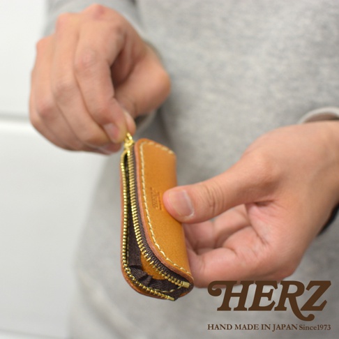 職人手作皮革印章收納袋，採用天然皮革製作，呈現溫潤的棕褐色。拉鍊為金色，搭配深棕色內襯，整體設計簡約實用。