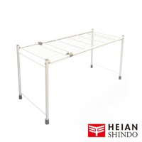 一個純白色金屬網格架，支架為白色金屬管，兩側腳部有灰色防滑墊，架子中間有可伸縮的調節裝置，右下角有平安伸銅的標誌。