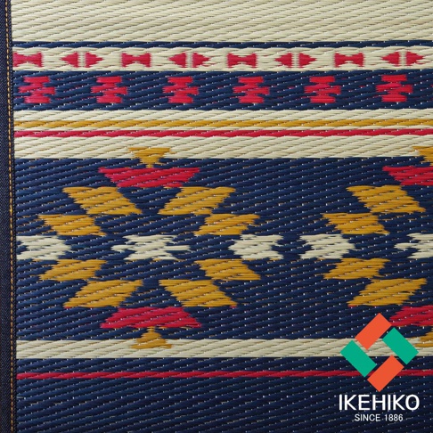 藺草編織瑜珈墊，深藍色底布，點綴著紅色、黃色和米色的幾何圖案，邊緣有紅色和黃色條紋。