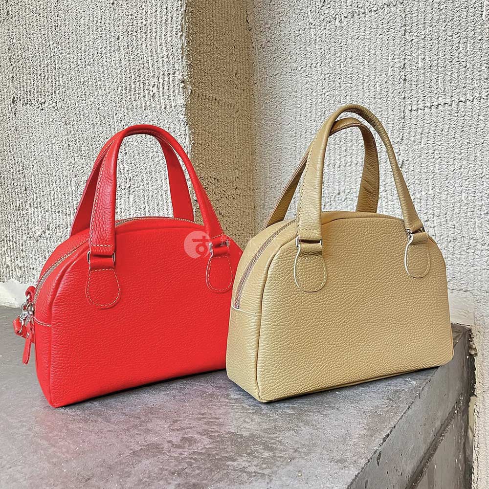 兩款京都職人手作半月迷你手提包，一款為鮮紅色，另一款為淺卡其色。兩款包皆為皮革材質，帶有雙提把設計，並以拉鍊封口。