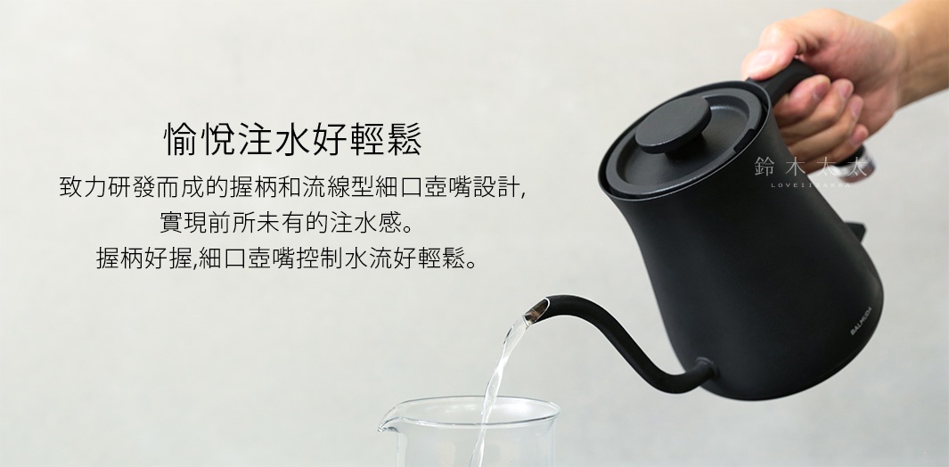 黑色啞光材質手沖壺，配有圓形壺蓋和細長彎曲壺嘴，手柄設計方便抓握，壺嘴正在向玻璃杯中注入細長的 and steady 水流。