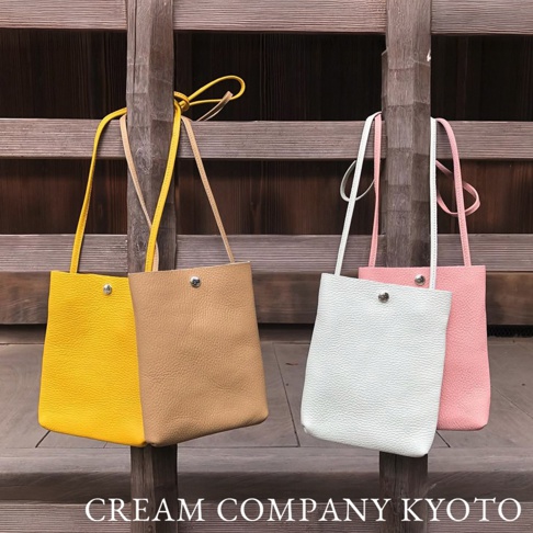 四款京都職人手作隨身手機包，分別為亮黃色、淺棕色、淺綠色和粉紅色，皆為皮革材質，設計簡約，配有細長背帶和單顆金屬釦開合。