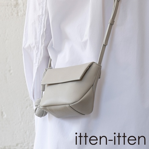 itten-itten 品牌淺灰色義大利皮革點結吊飾迷你單肩包，斜掛於穿著白色襯衫的模特身上。