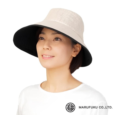 一位女性戴著一頂淺米色、寬緣遮陽帽，帽檐內側為黑色。帽子頂部材質有細緻的紋理。