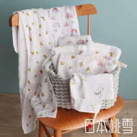 一把木椅上放著一籃子印有可愛圖案（如彩虹、檸檬、月亮和星星）的白色紗布方巾，其中一條較長的紗布毛巾懸掛在椅子扶手上。