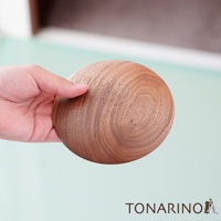 手持一顆圓形天然實木門擋，木紋清晰，顏色為溫潤的木棕色。