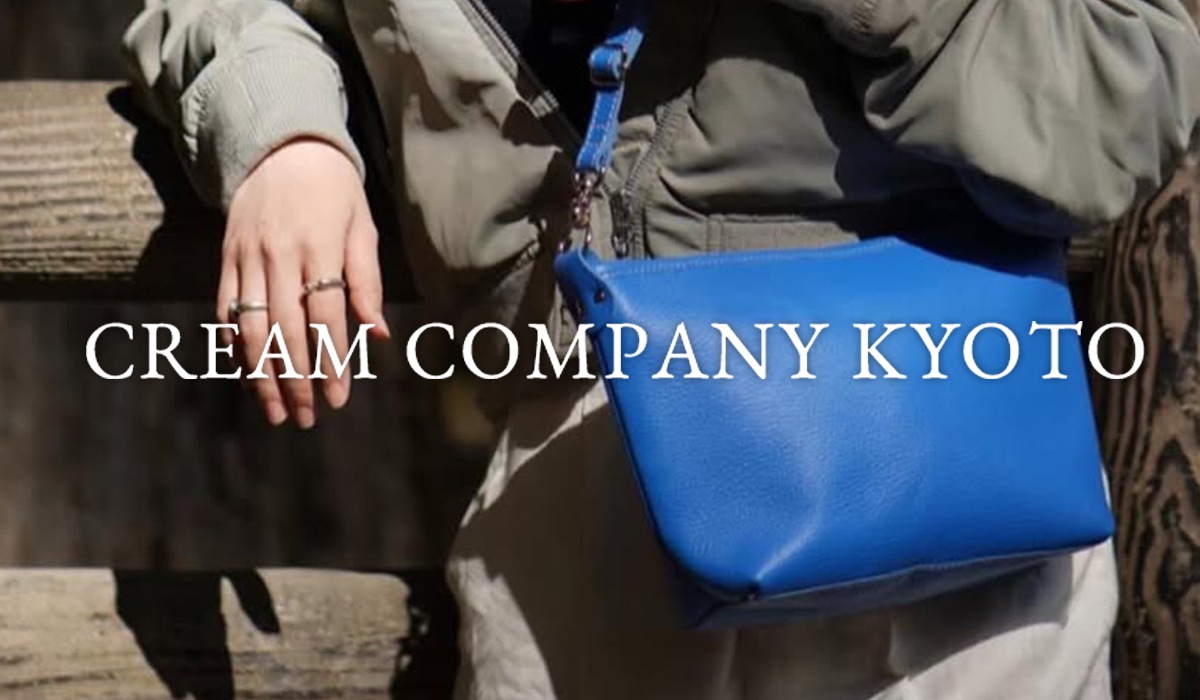 手持藍色皮革包的特寫，包上印有CREAM COMPANY KYOTO字樣